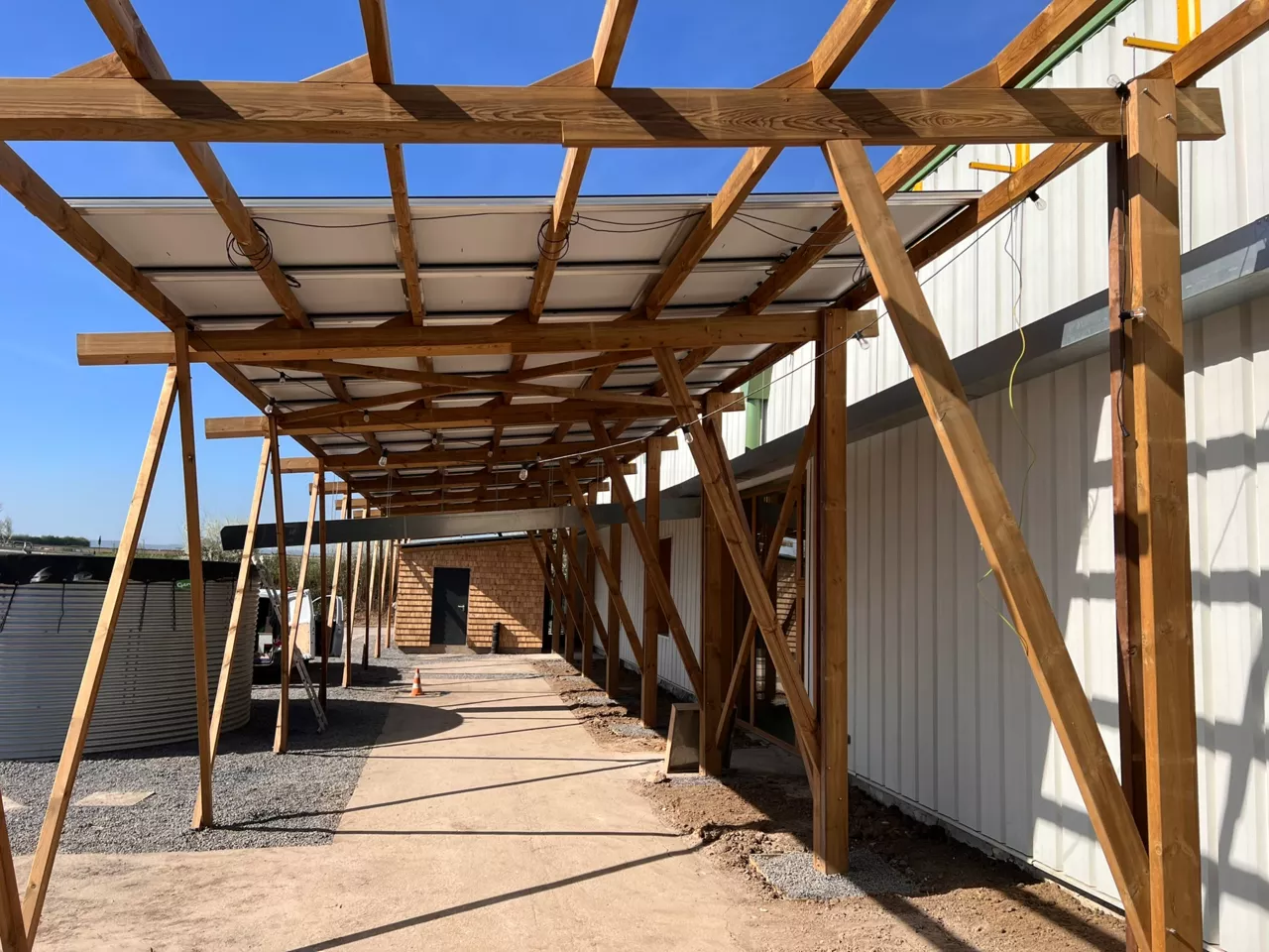 Ombrière en structure bois servant de support à des panneaux photovoltaïques sur le site démonstrateur de Noeux-environnement, alliant matériaux biosourcés et production d’énergie renouvelable