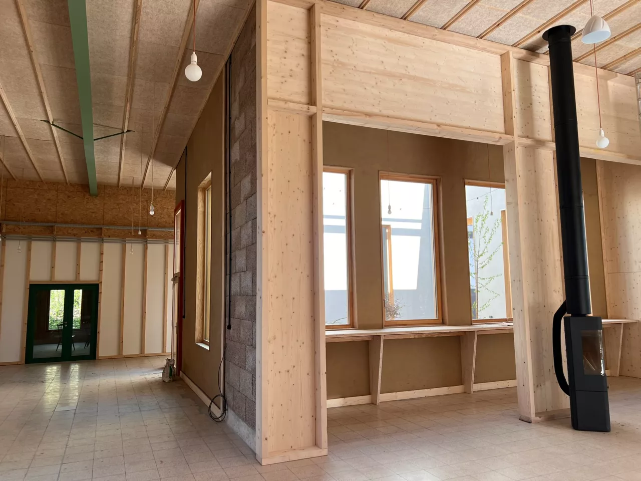 Intérieur du bâtiment démonstrateur de Noeux environnement, associant ossature bois, enduits terre et poêle à bois, pour un exemple concret de construction biosourcée et durable.